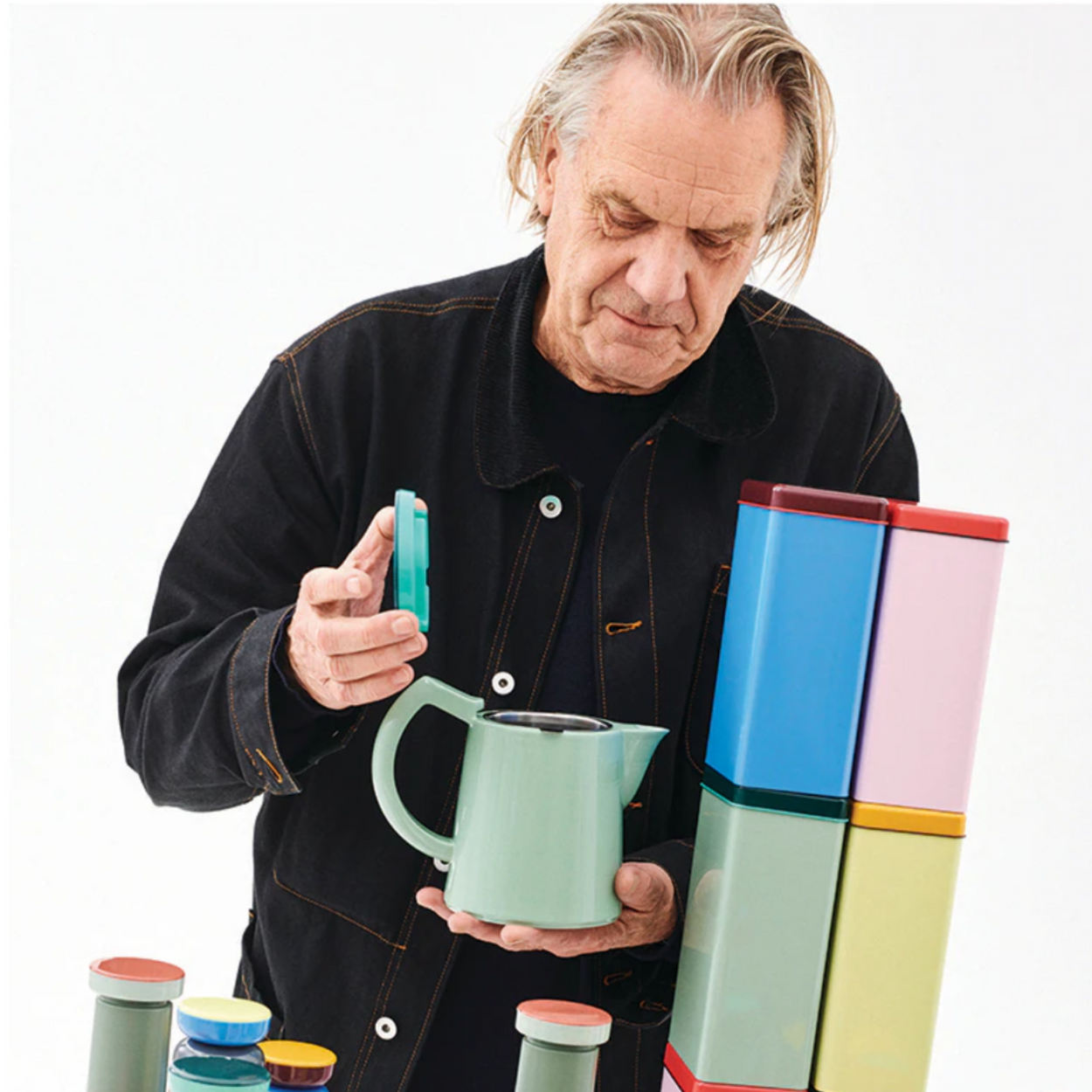 George Sowden holding a green mug with colourful stacked mugs in the background