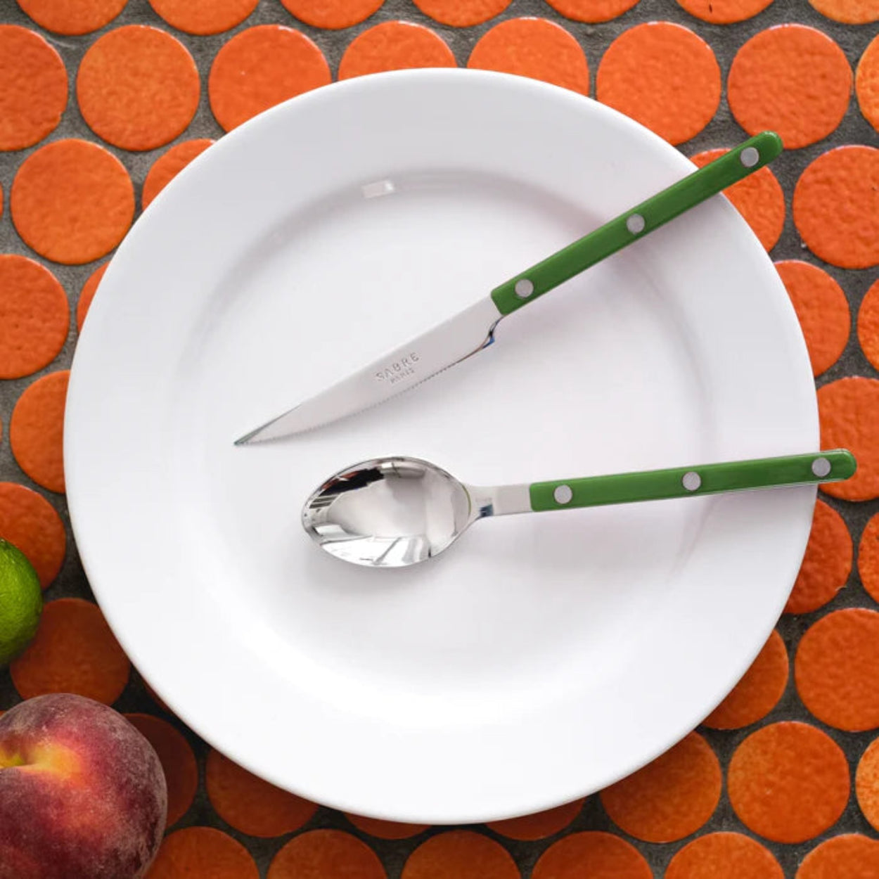 Mixed colour Sabre Paris Bistrot Cutlery 4 Piece Sets on orange circle tile backdrop.
