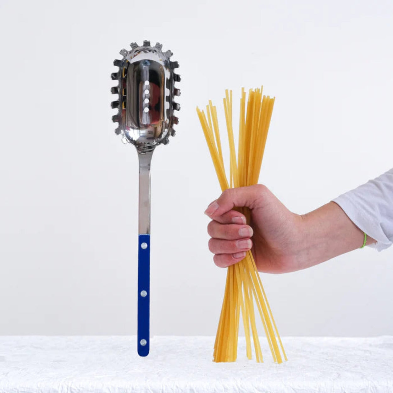 Womens hand holding pasta next to a Navy Sabre Paris Bistrot Spaghetti Server