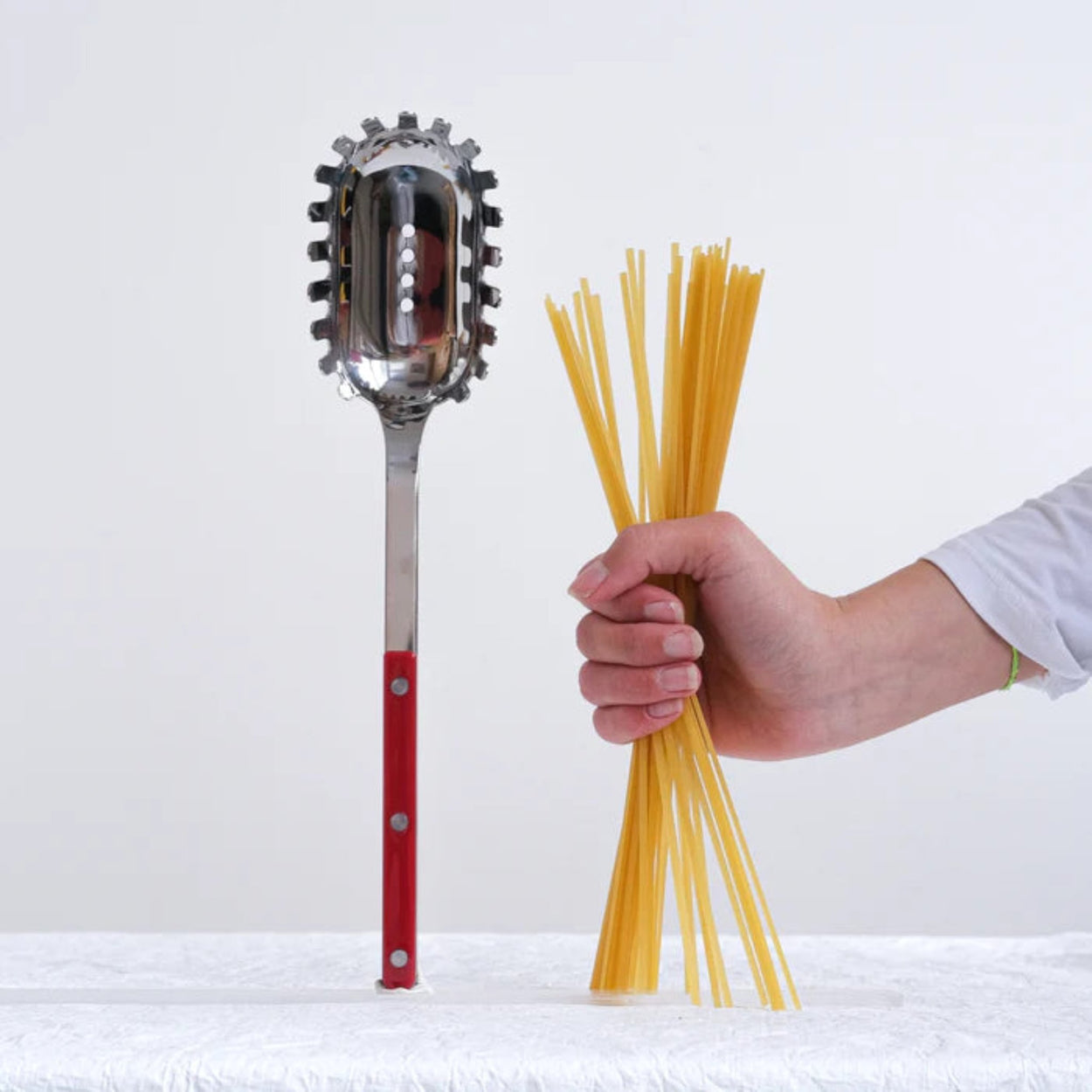 Womens hand holding pasta next to a Burgundy Sabre Paris Bistrot Spaghetti Server