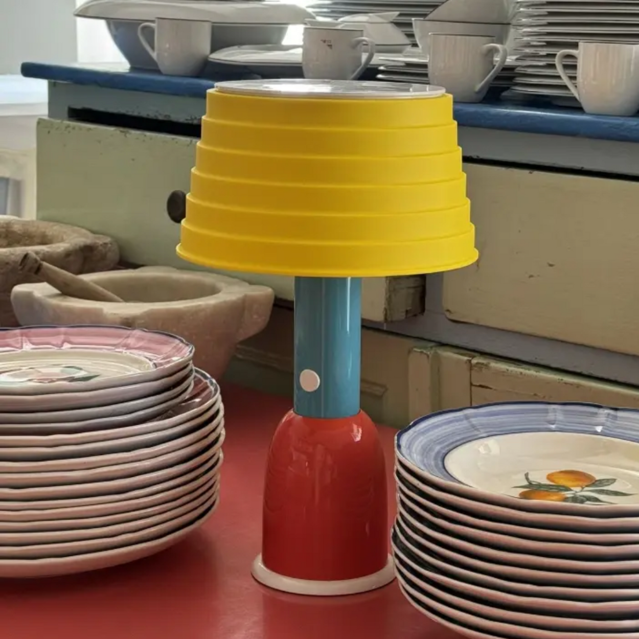 Colorful lamp with stacked plates in a kitchen setting