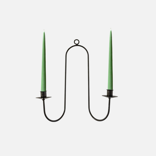 Black metal candle holder with two green candles on a white background