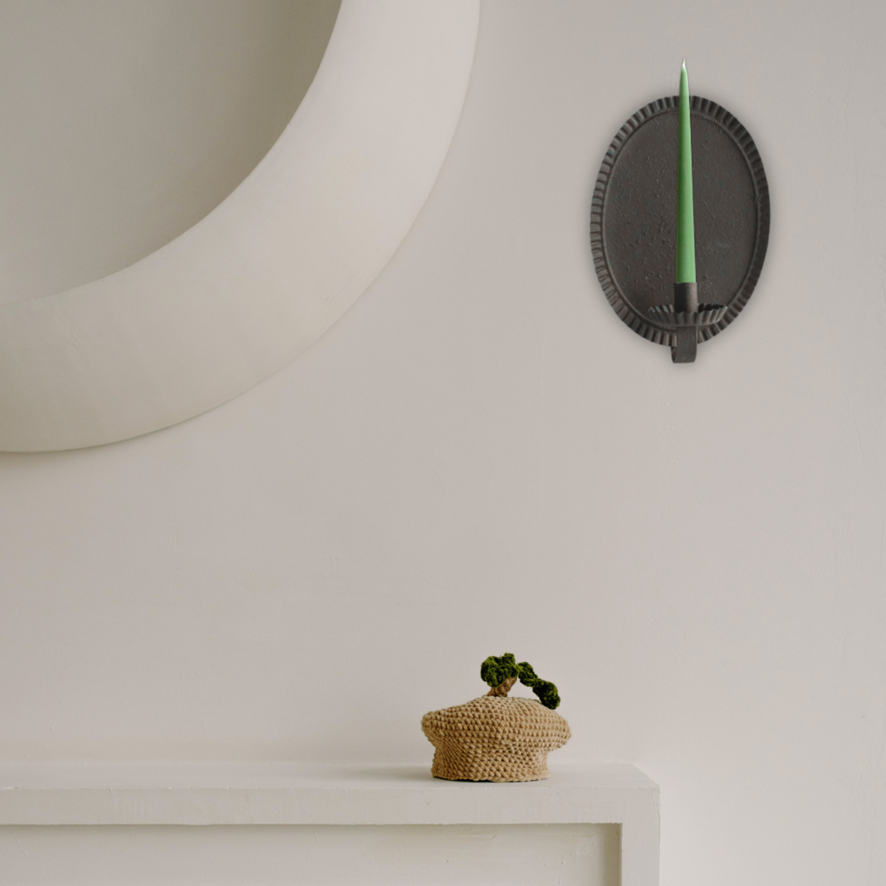 Decorative wall sconce with a green candle on a neutral background
