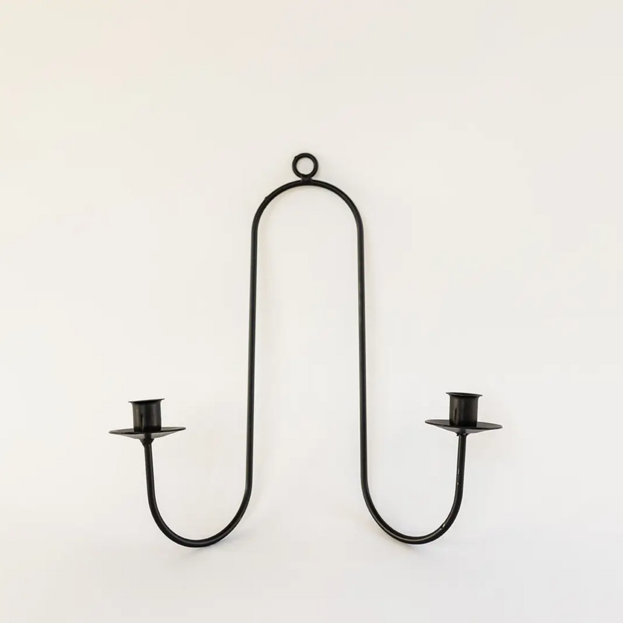 Black metal wall-mounted candle holder on a white background