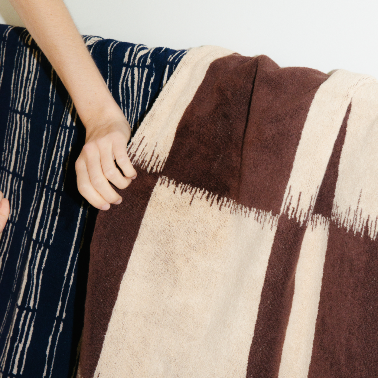 n Sonata Karin Bath Sheet on rail with womans hand reaching.