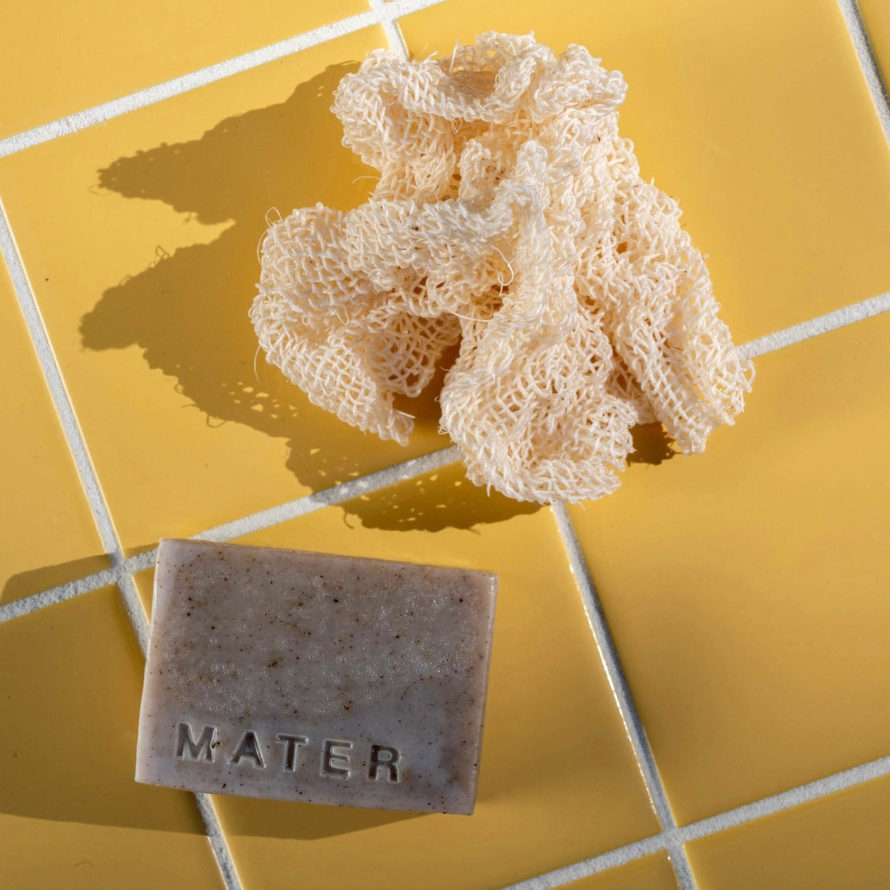 Mater Soap bar and Agave Cloth on a yellow tile backdrop.