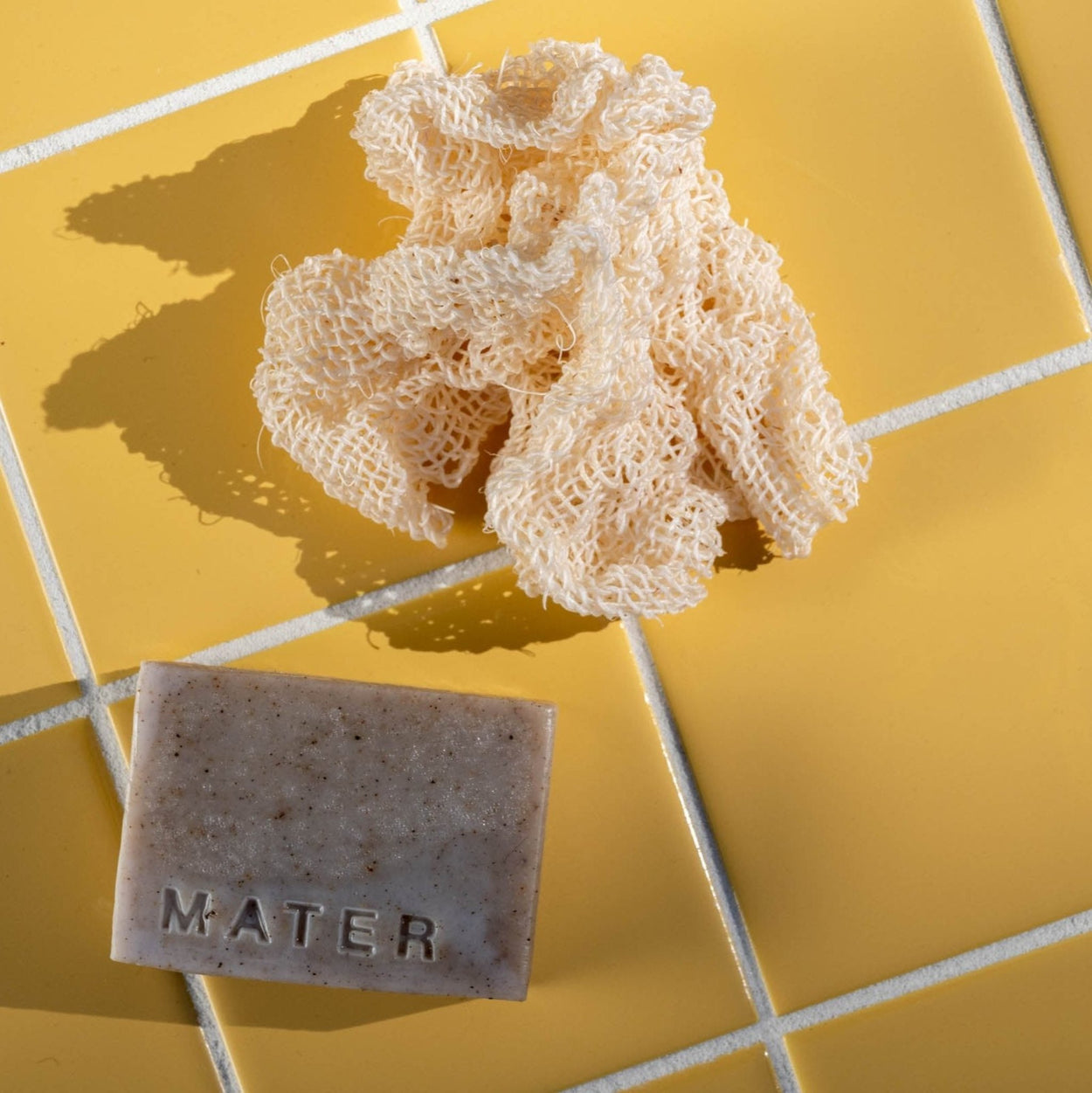 Mater Agave Cloth scrunched next to Mater soap bar on yellow tilesbackgroundd