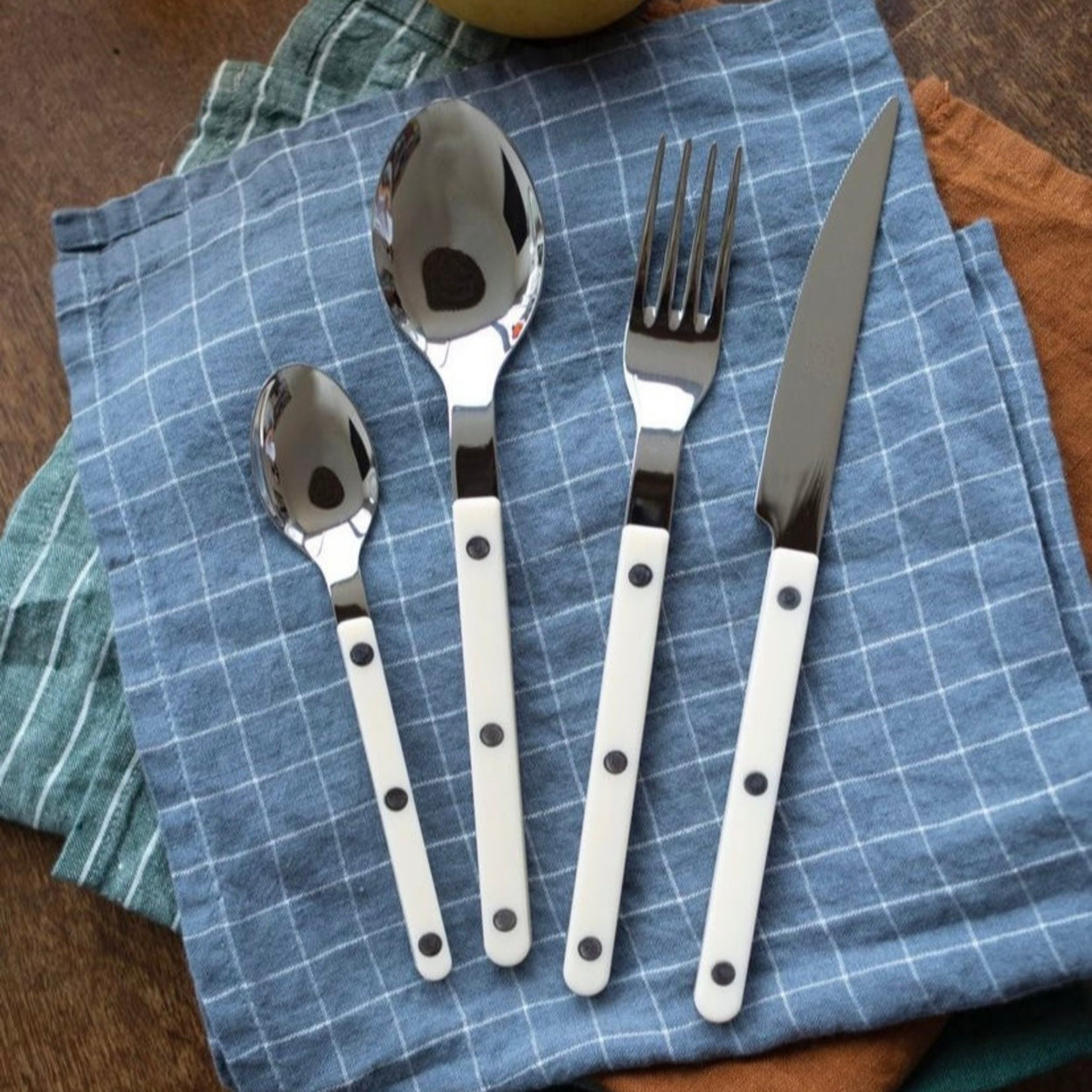 Sabre Bistrot Cutlery 4 Piece Set - Ivory on blue check napkin.