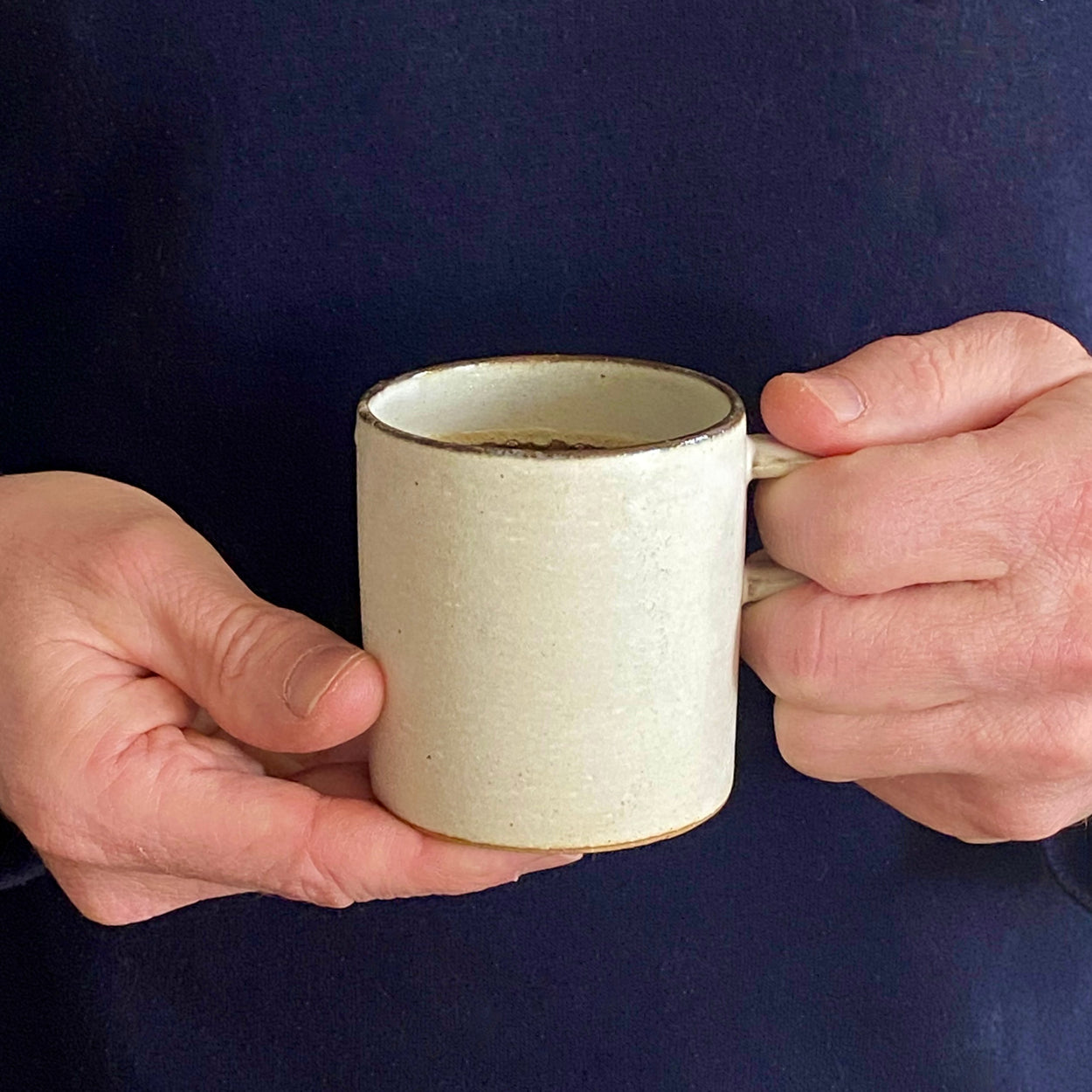 Man holding Japanese Ceramic Birch tall cup against blue backdrop.