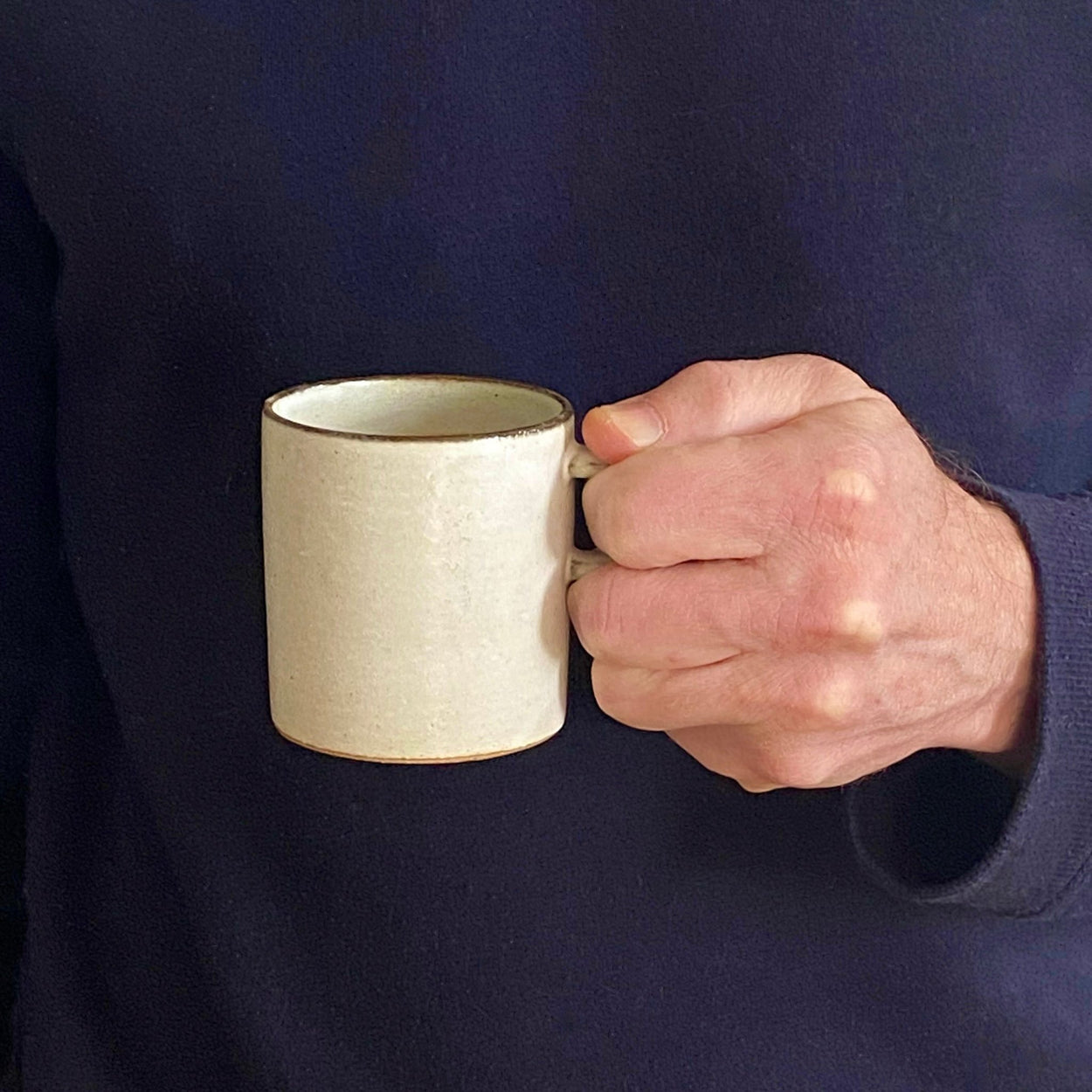 Man holding Japanese Ceramic Birch tall cup against blue backdrop.