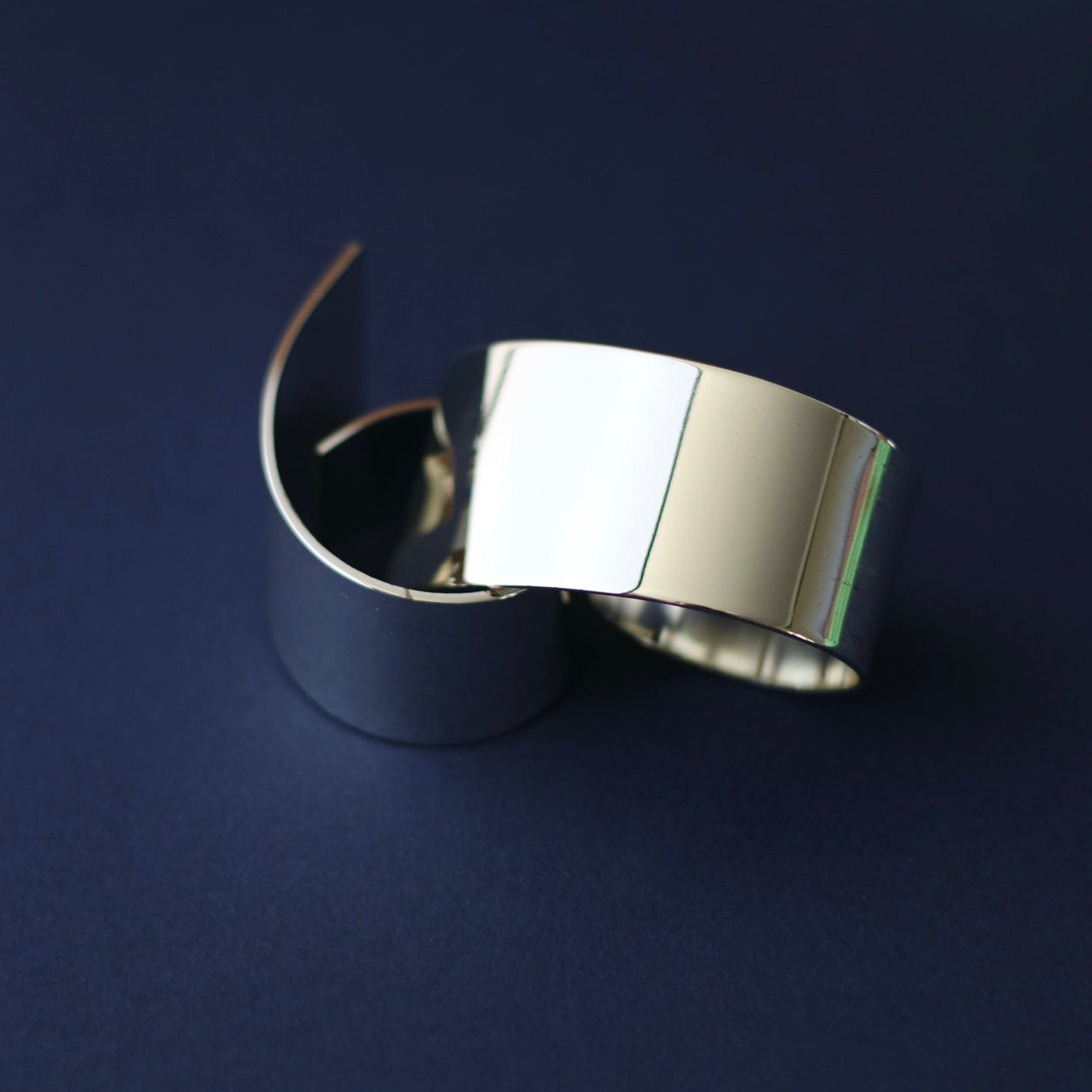 Vintage 2 silver plate napkin rings against dark blue backdrop.