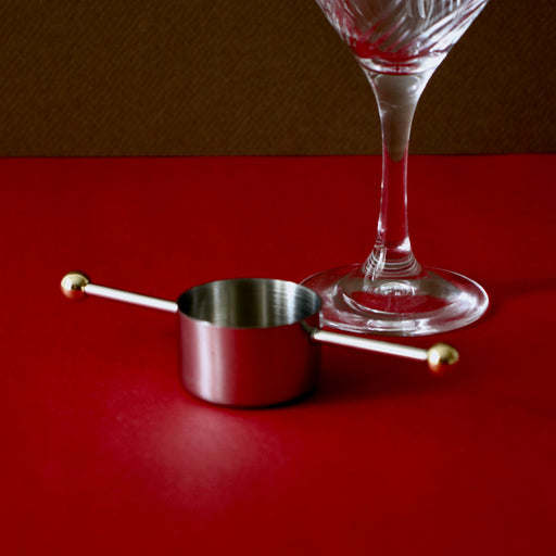 Japanese Cocktail Jigger with martini glass against a red backdrop.