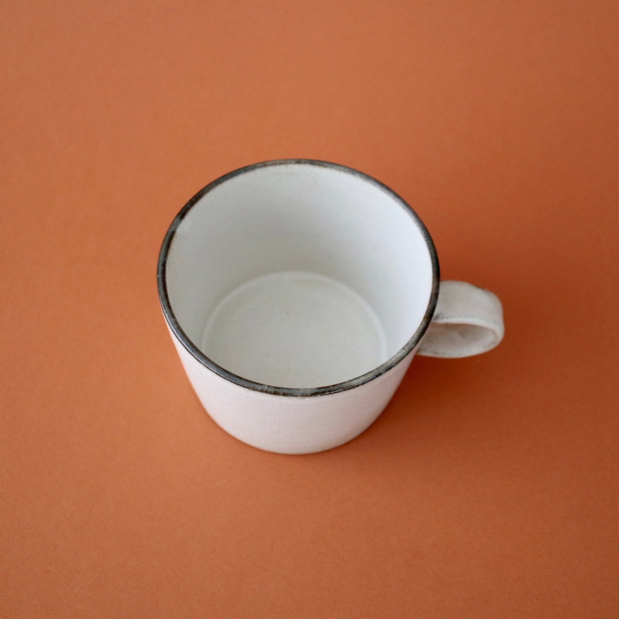 Inside of Japanese Ceramic Birch Cup against orange backdrop.