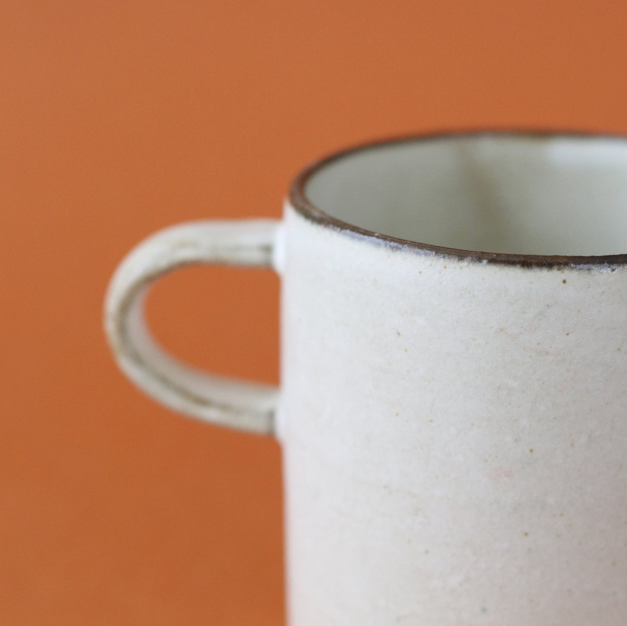 Close up pf Japanese Ceramic Birch tall cup against orange backdrop.