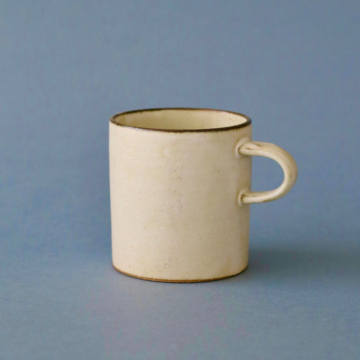 Japanese Ceramic Birch tall cup against blue backdrop.
