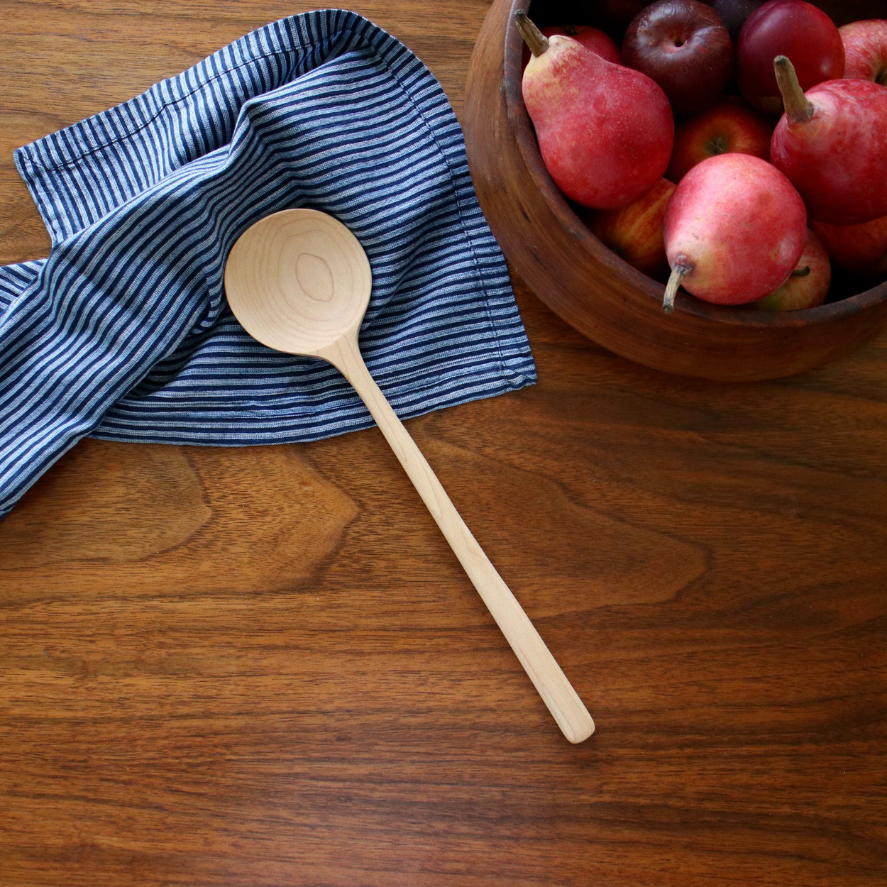 Hand crafted maple wood spoon on wood table with blue napkin