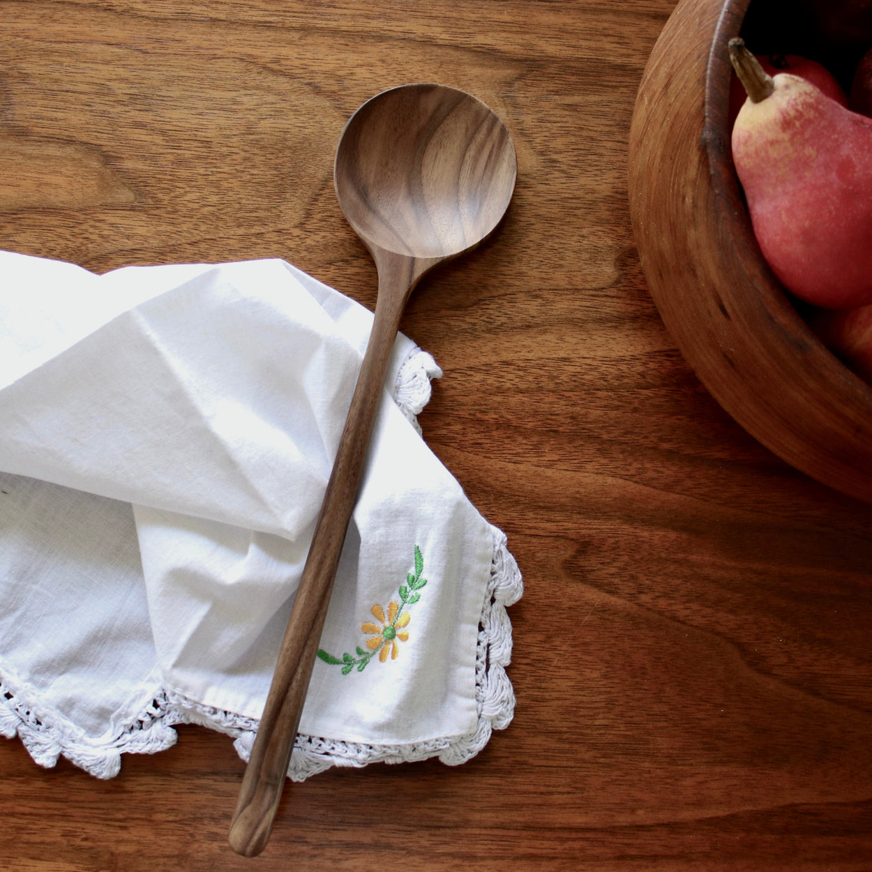 Hand crafted walnut wood spoon on white napkin with floral embroidery