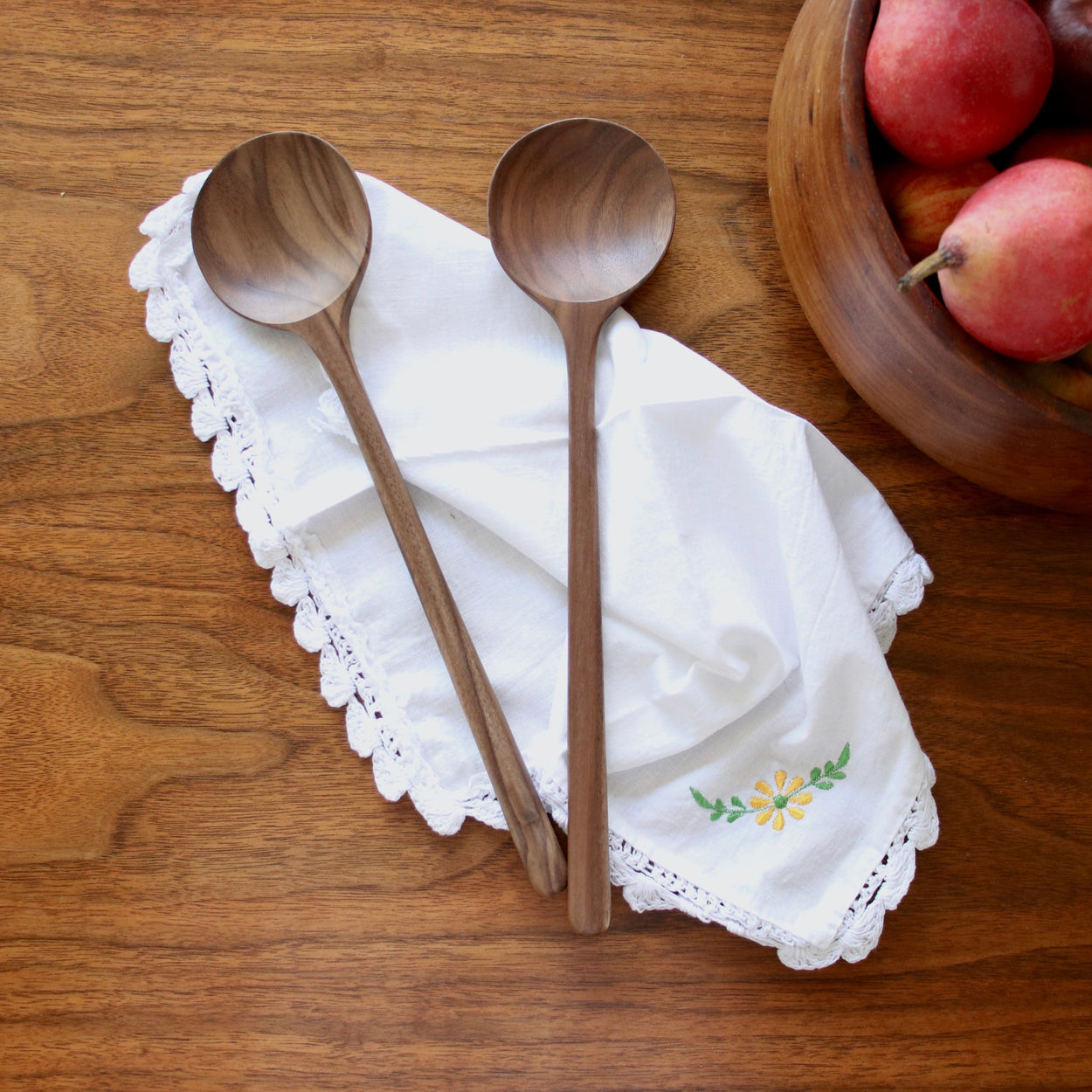 Two Hand crafted walnut wood spoons on wood table with napkin