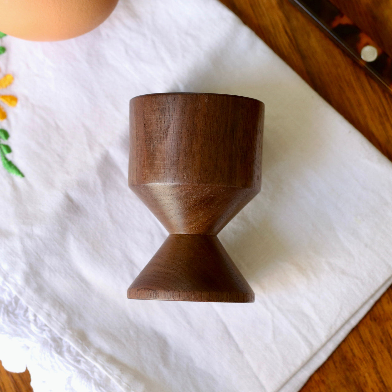 Hand crafted walnut wood egg cup lying sideways on wood tabletop