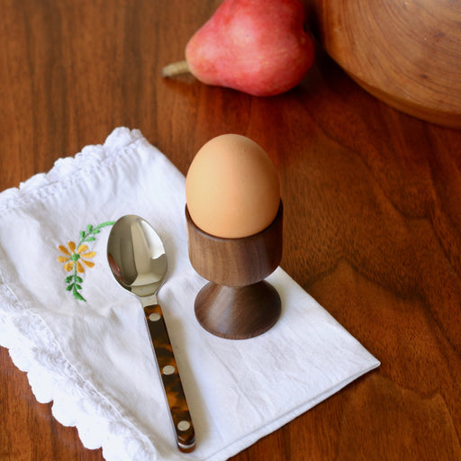 Hand crafted walnut wood egg cup with egg and Sabre Paris spoon and napkin on wood tabletop