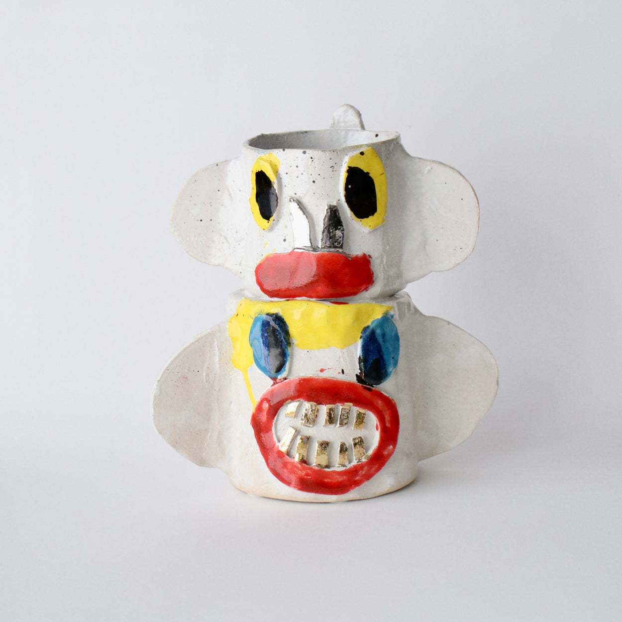 Ceramic vase with a face design on a white background