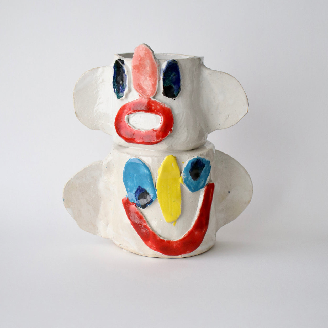 Ceramic vase with abstract face design on a white background