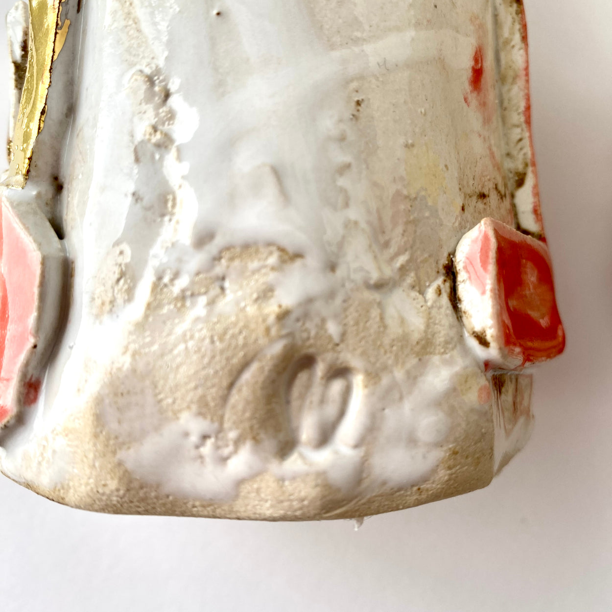 Close-up of a ceramic figurine with white glaze and pink accents on a white background