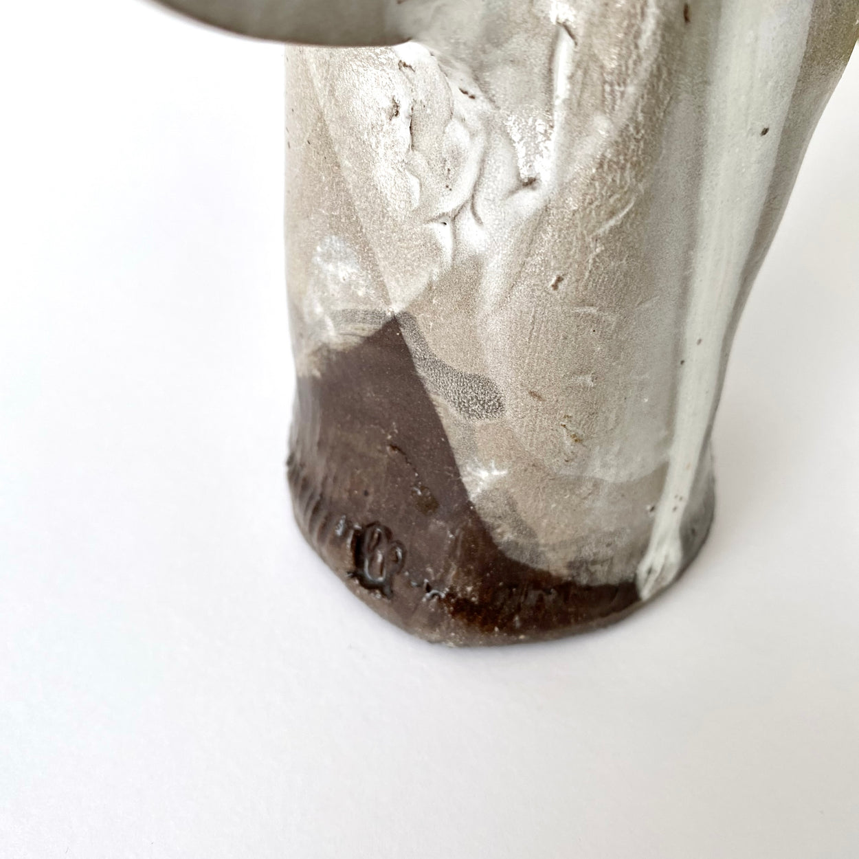 Close-up of a ceramic vase base with a textured surface on a white background