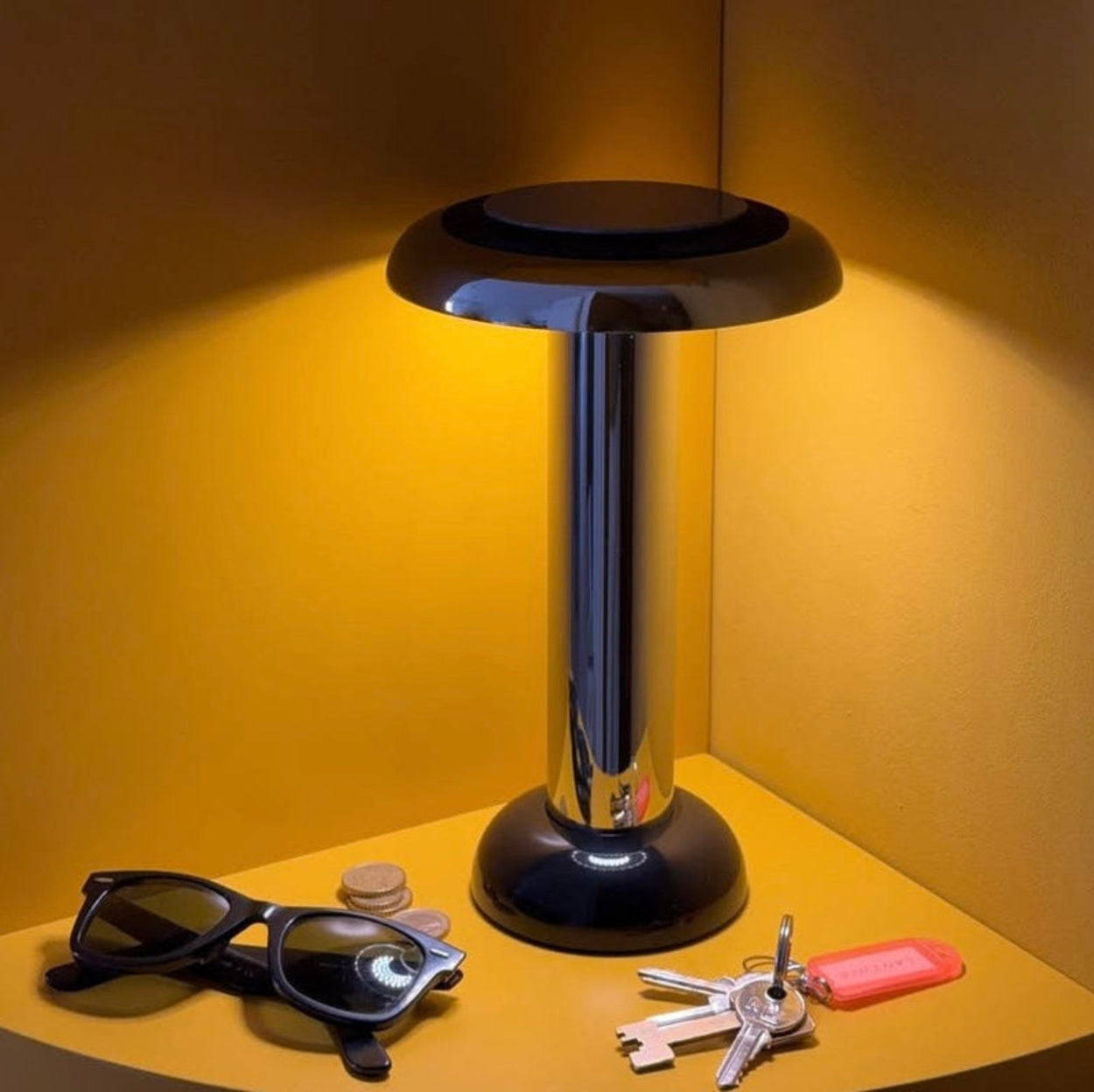 Sowden Pl6 chrome lamp on a yellow surface with sunglasses and keys around it