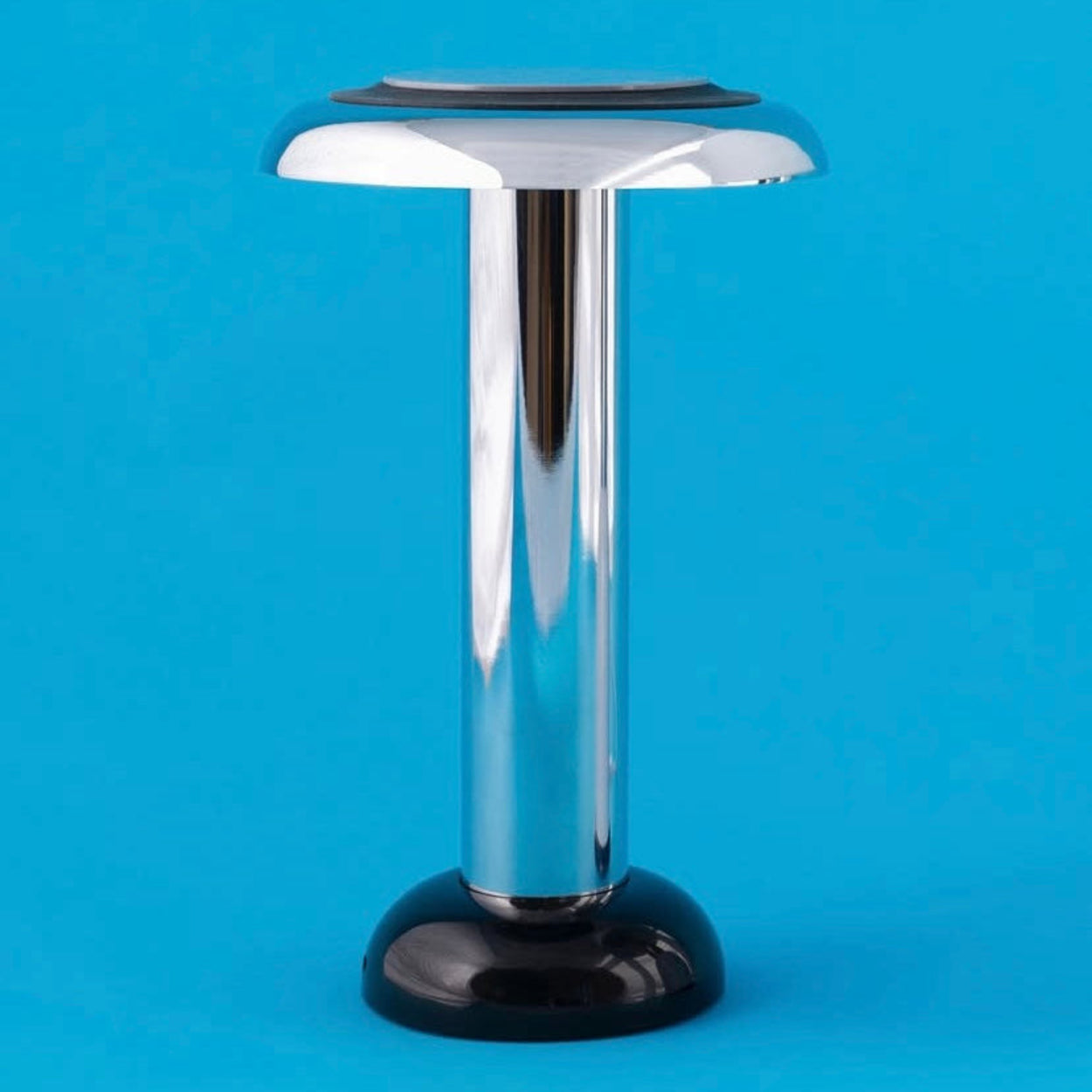 Chrome Sowden Pl6 lamp with a flat top on a blue background