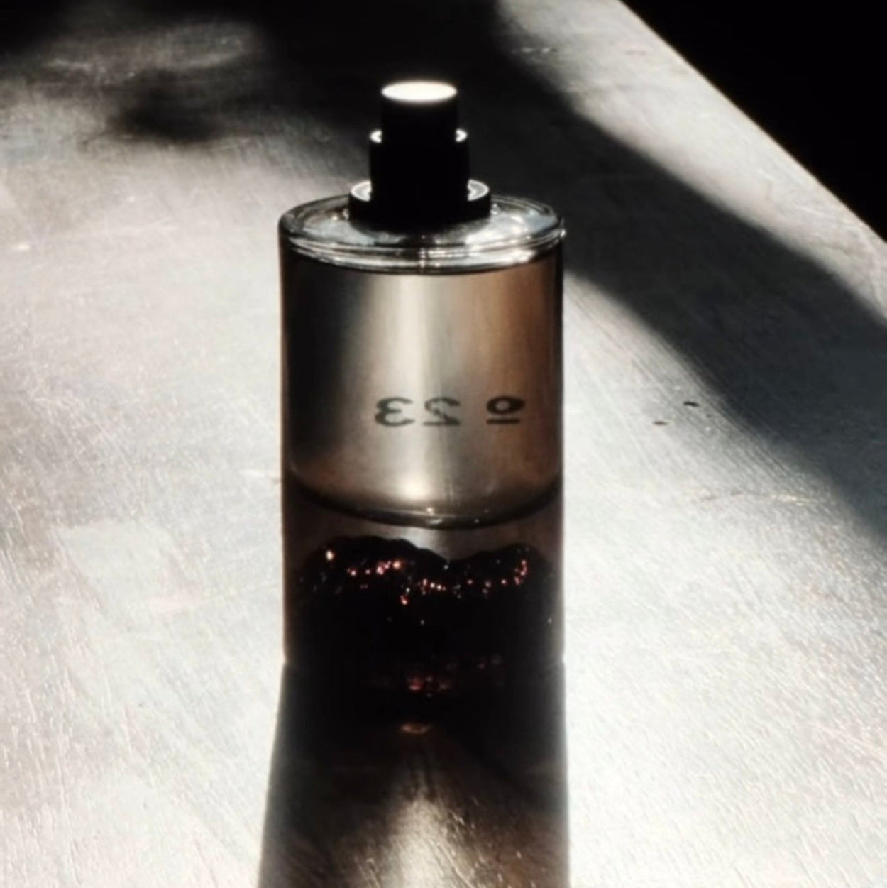 Silver perfume bottle with '023' on a textured surface