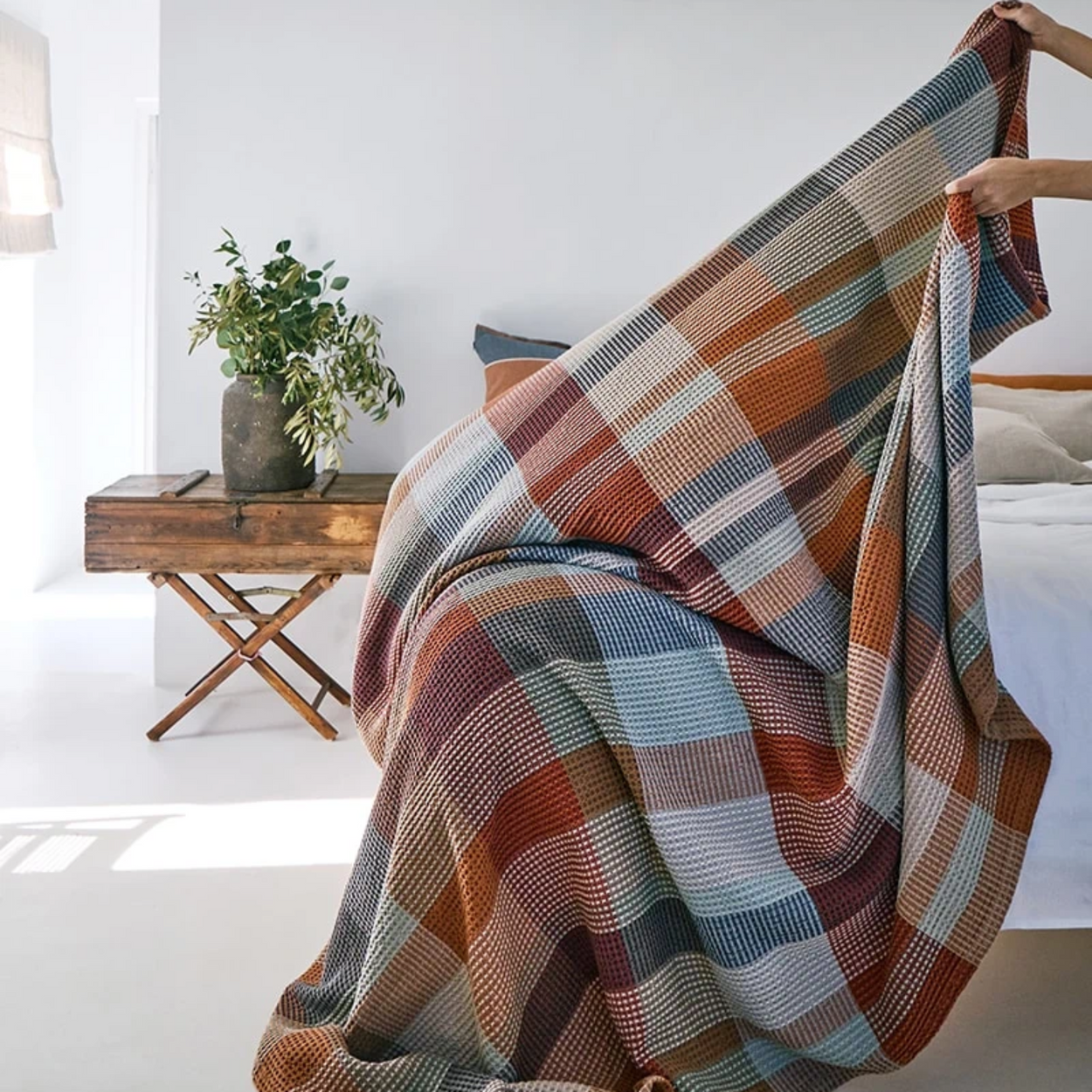 Mungo Vrou-Vrou Cotton Waffle Blanket - Cedarwood being draped on bed by person off screen