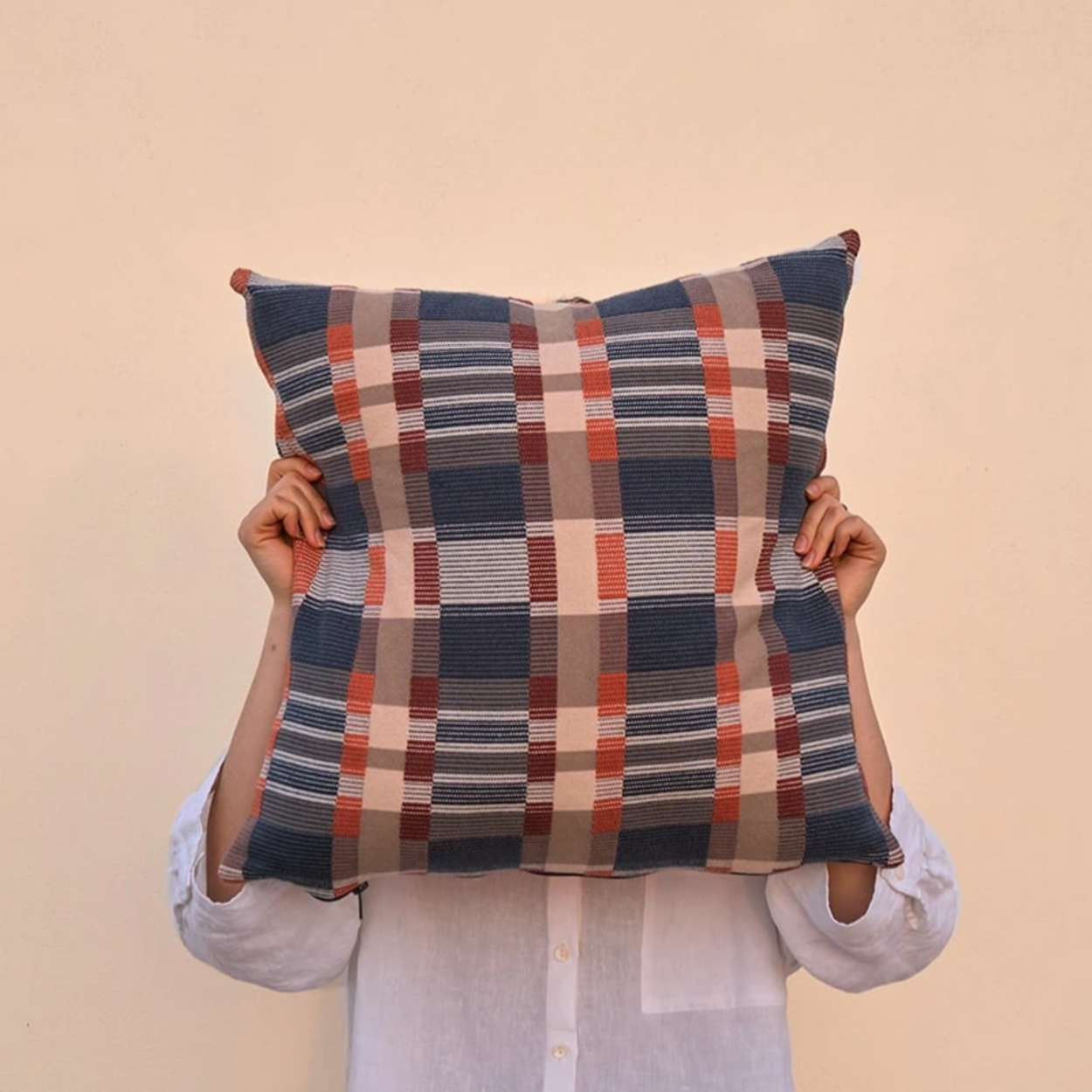 Woman holding blue Mungo Skipping Block Cushion in front of her head for scale.