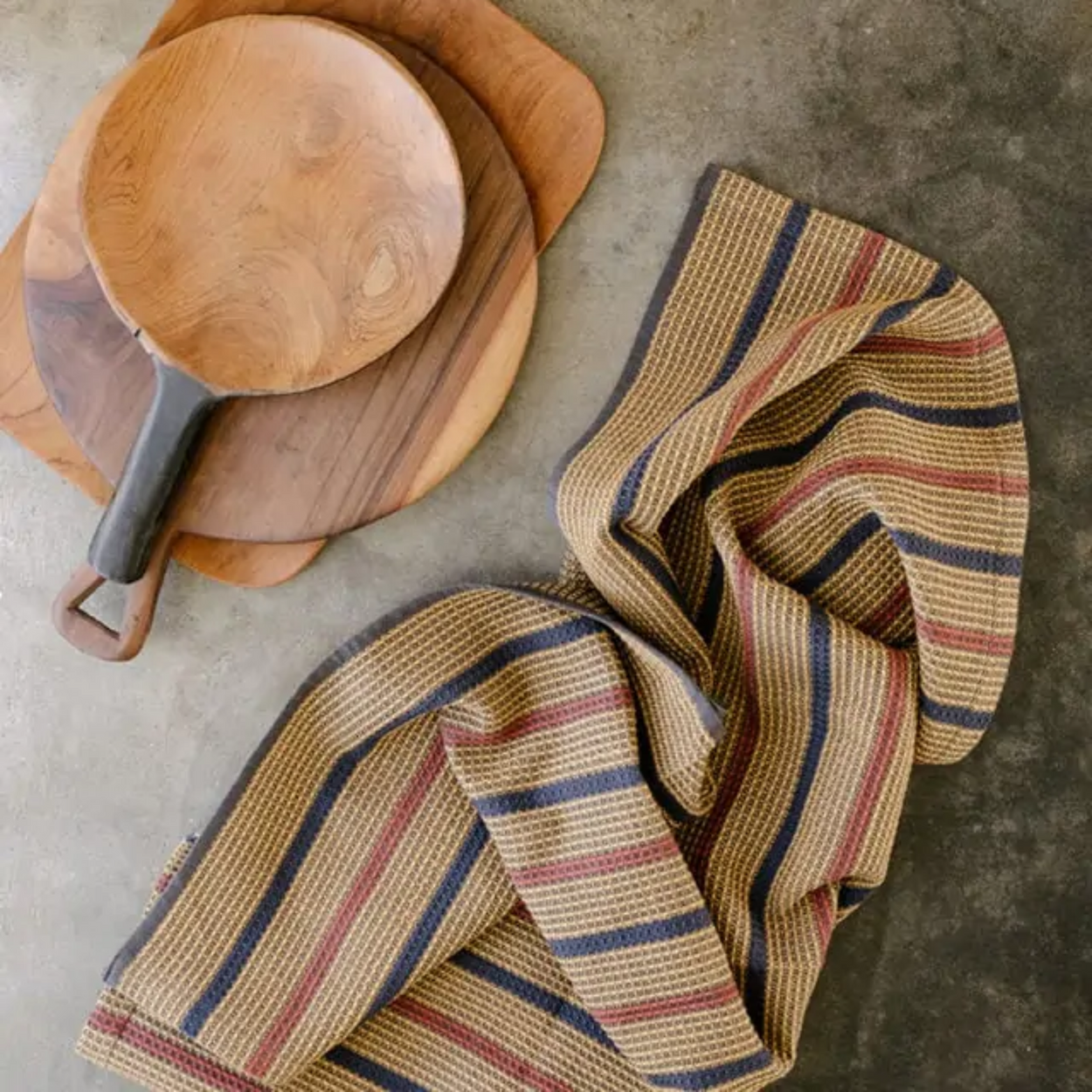 Mungo Waffle Tea Towel in Ochre brown on concrete with wood cutting boards.
