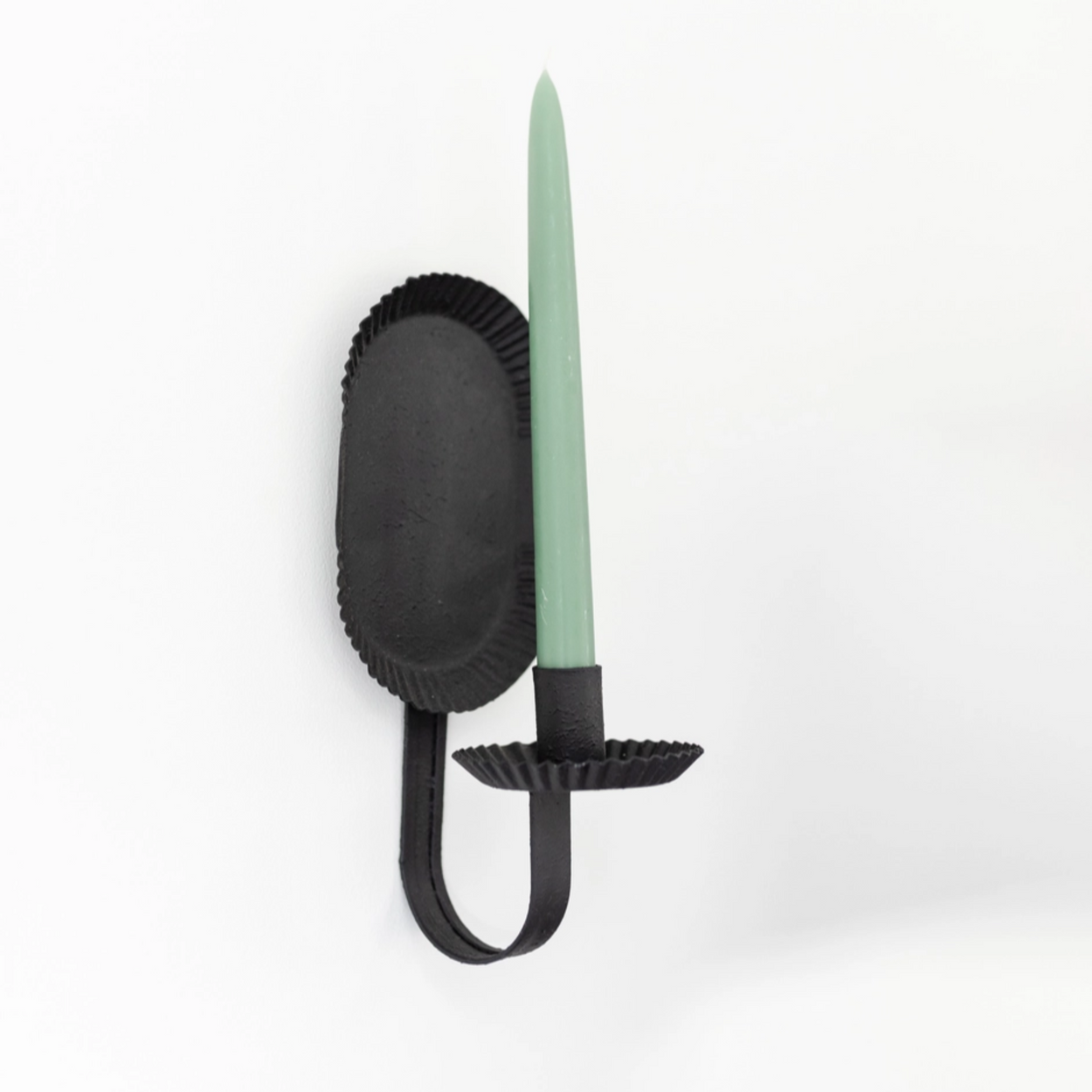 Amish Petit Candle Sconce with green candle wall-mounted on a light grey background
