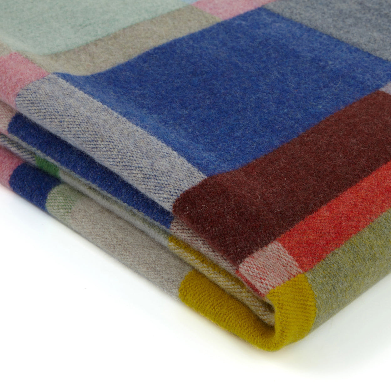 Folded multicoloured wool blanket with a checkered pattern on a white background