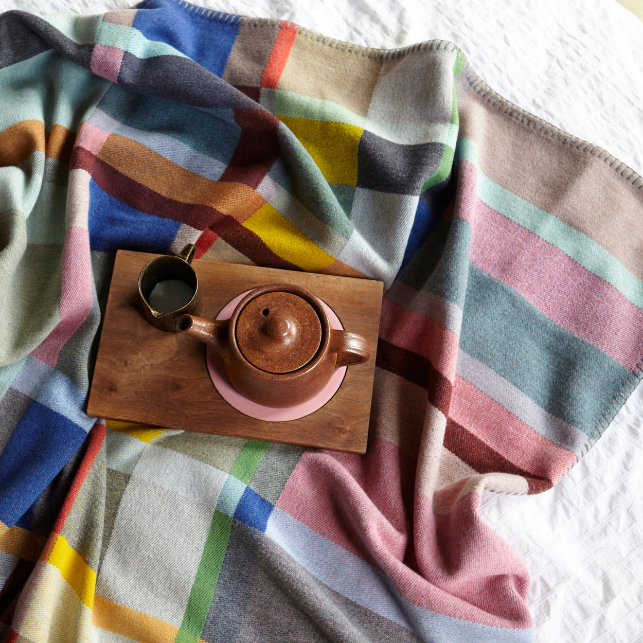 Close up of lloyd blanket on bed with teapot.