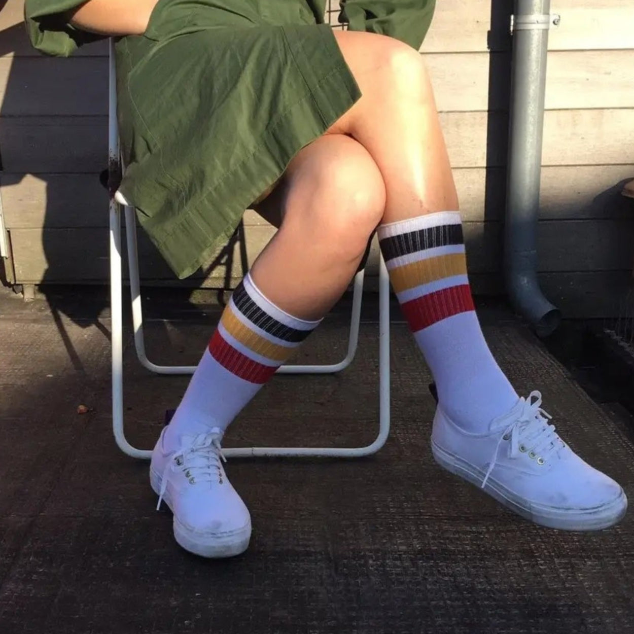 A woman in a skirt wearing Escuyer Striped Tube Socks with blue yellow stripe on white.