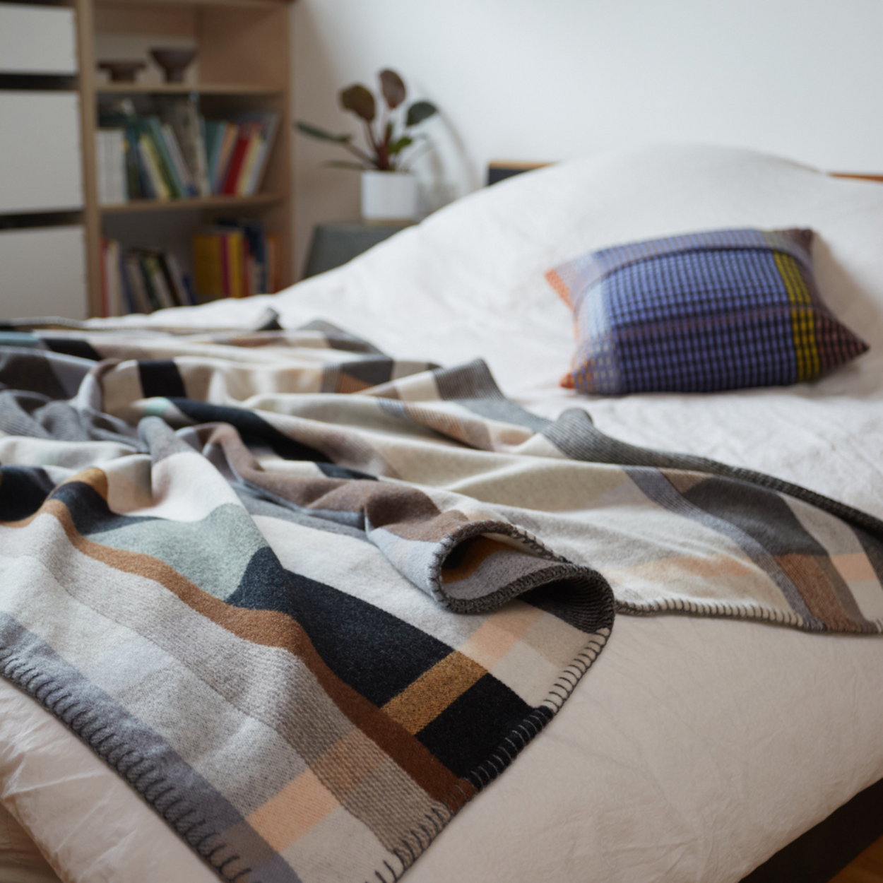 Wallace Sewell Premium Chippendale Merino lambswool throw in pale brown tones, draped on large bed.