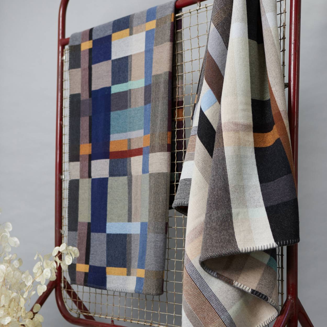 Wallace Sewell Premium Chippendale Merino lambswool throw in pale brown tones hanging on metal frame with Erno blanket