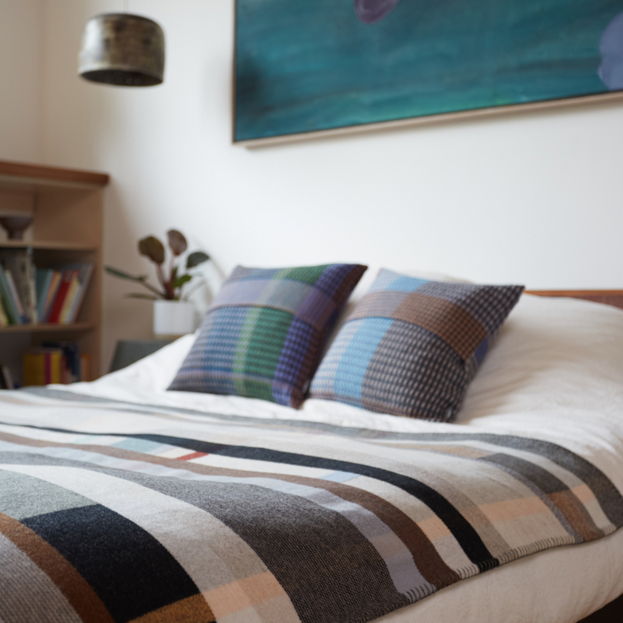 Wallace Sewell Premium Chippendale Merino lambswool throw on bed with blue painting overhead