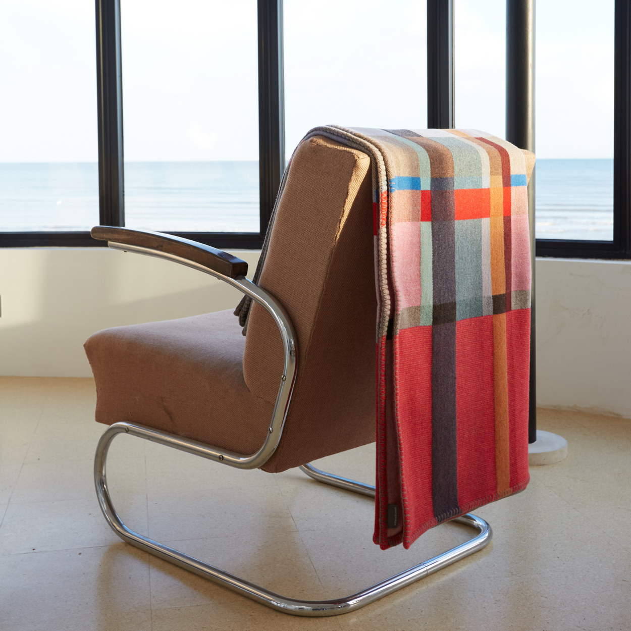 Wallace Sewell Premium Lasdun Merino Lambswool blanket folded on back of art deco chair by window.