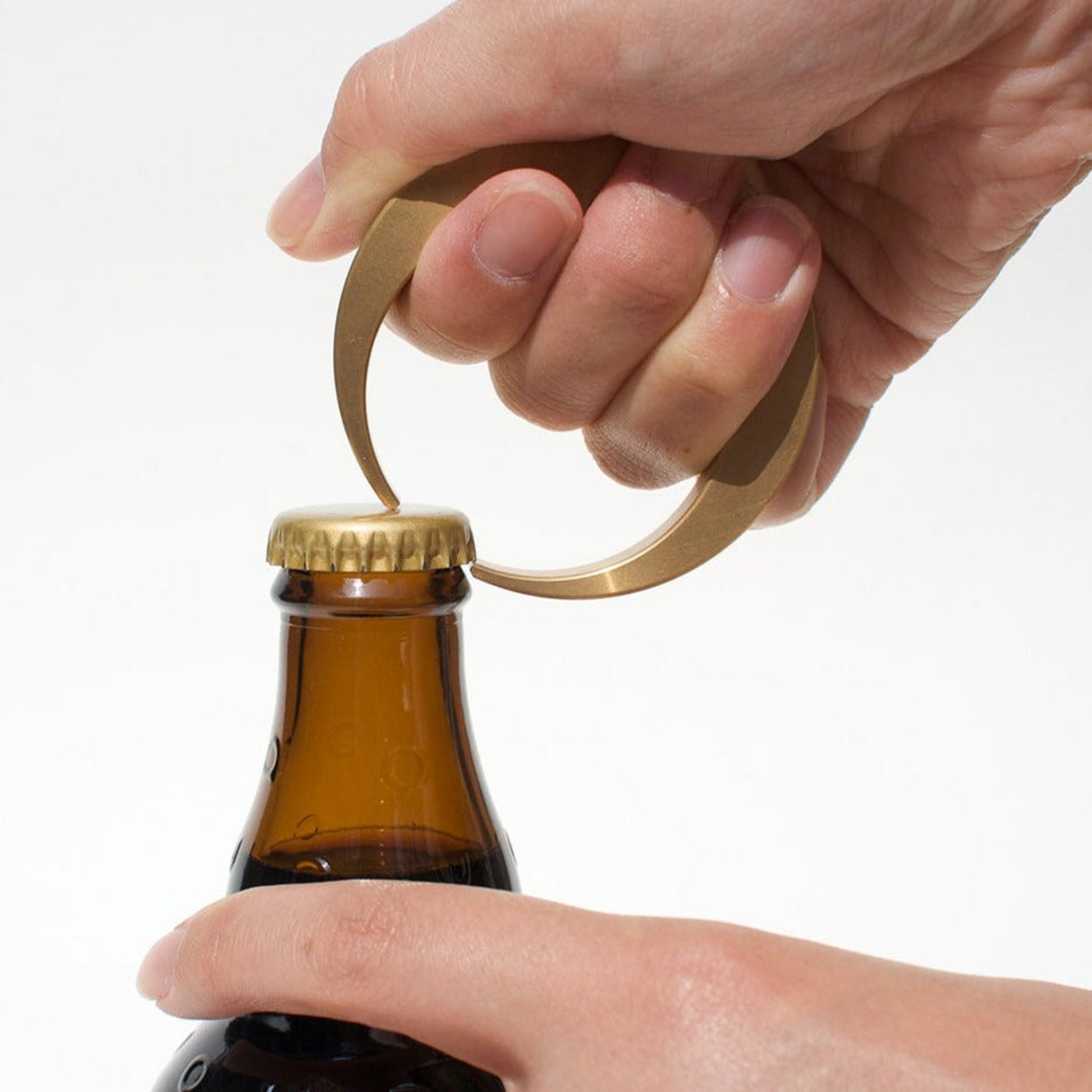 Futagami Crescent Bottle Opener being used to open beer bottle, held by hands.