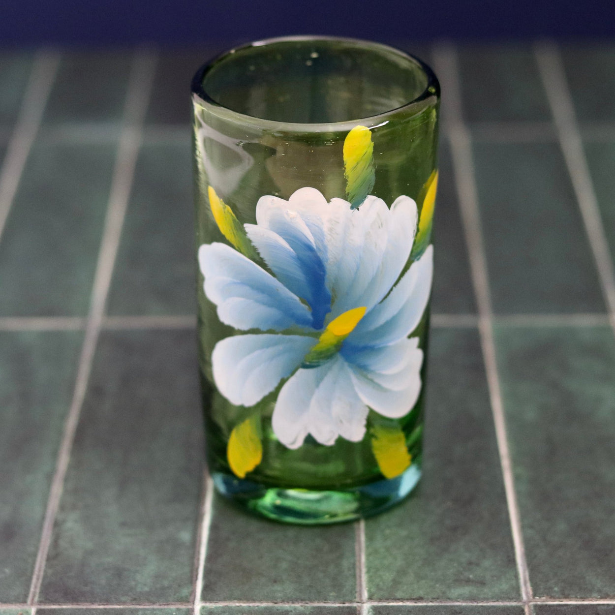 Floral hand painted glass tumbler against blue background