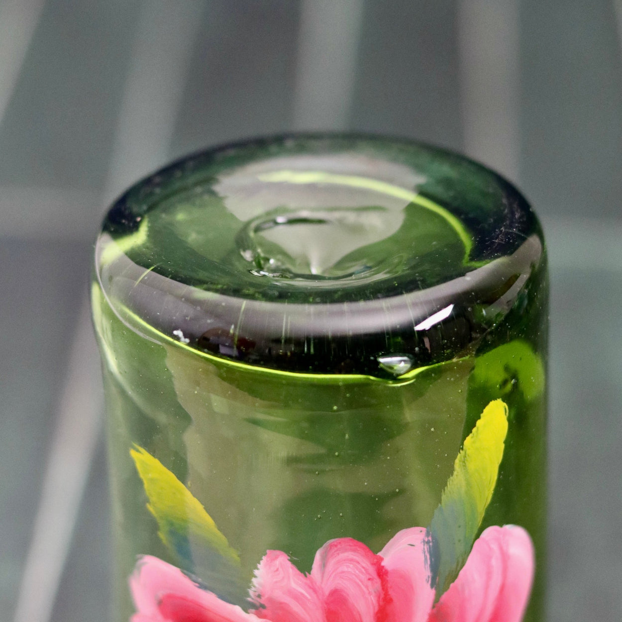 Bottom of Floral hand painted glass tumbler against blue background
