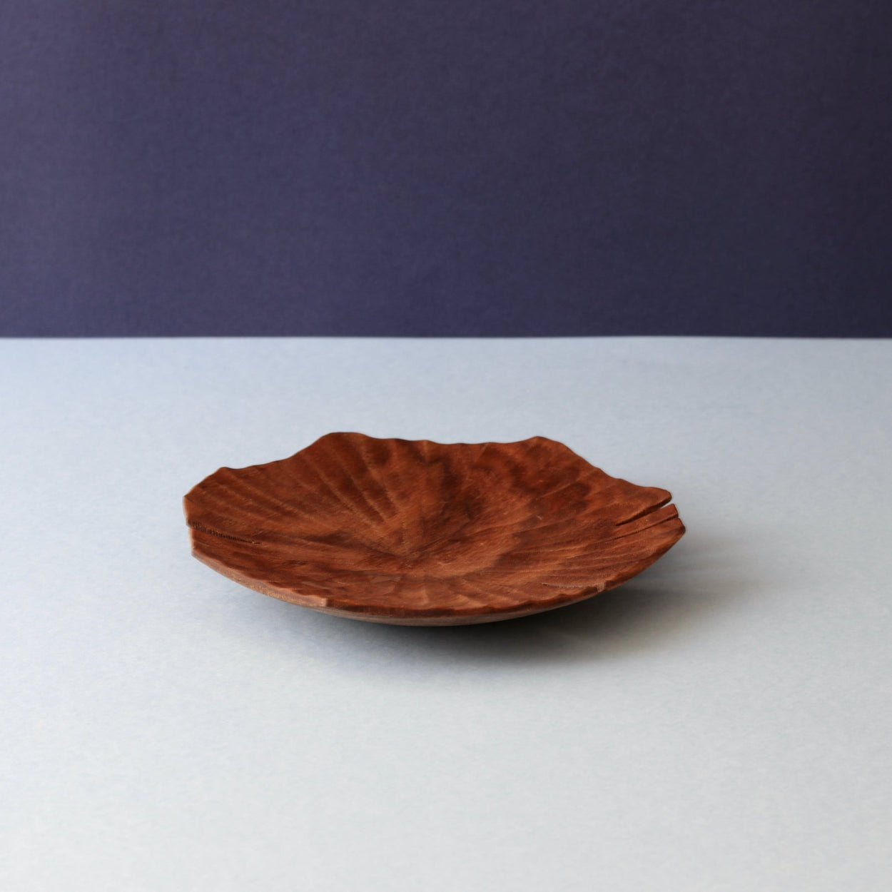 Hand carved Lotus leaf walnut wood plate on blue backdrop