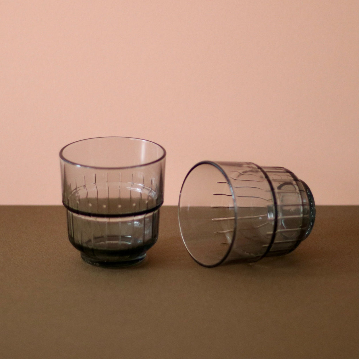 Smoky Grey Portuguese glasses x 2, one lying on it's side with brown and peach background.
