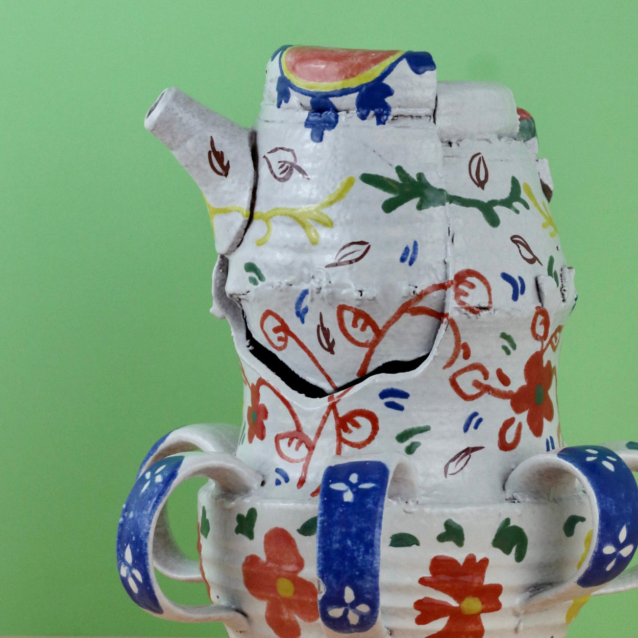 Handmade Ceramic Pentref Jug by Elin Hughes against a green and peach background. Close up top.