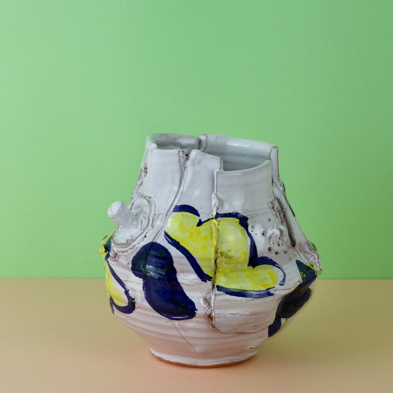 Modern Ceramic Vase by Elin Hughes against a light green and peach background, side view.