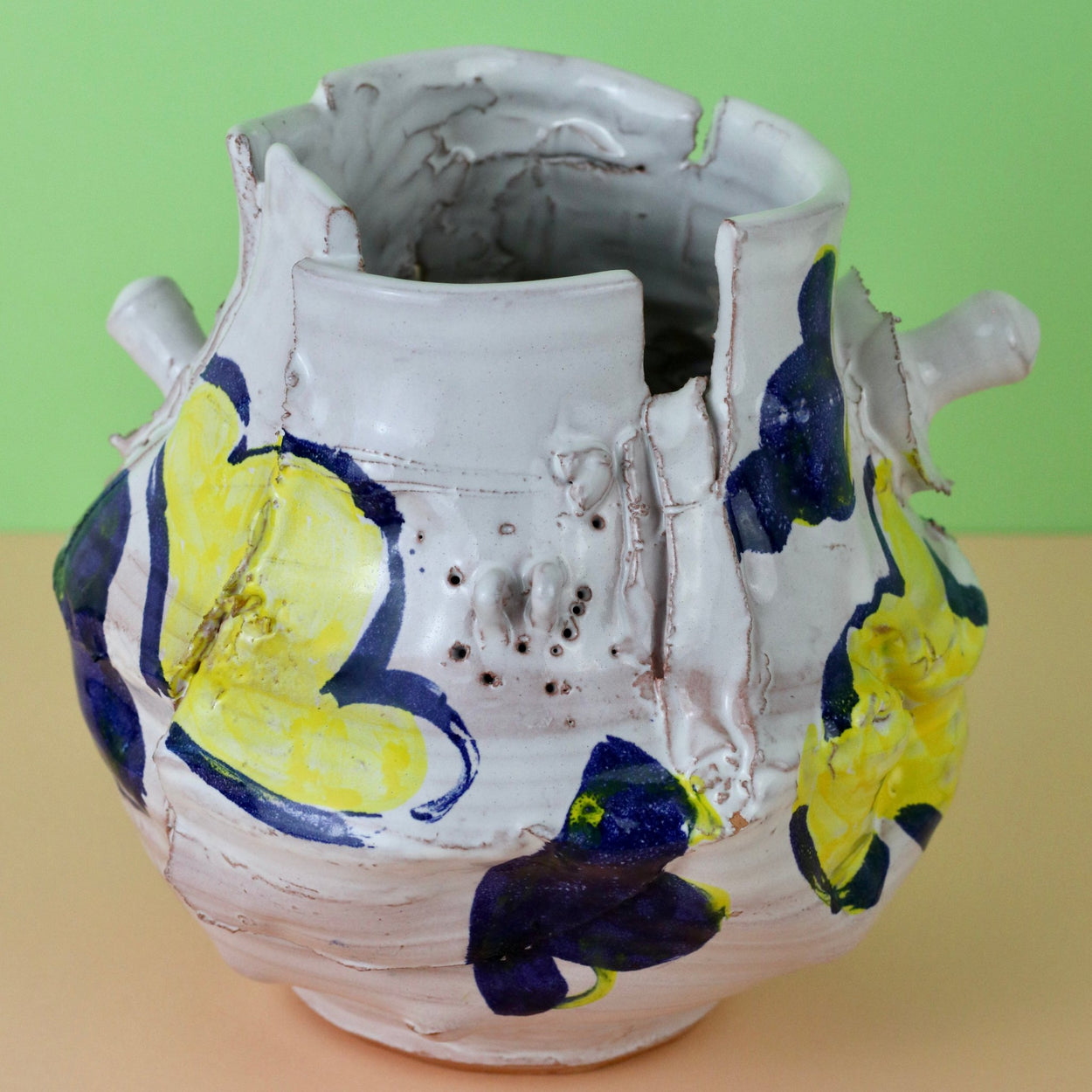 Modern Ceramic Vase by Elin Hughes against a light green and peach background. Close up view.